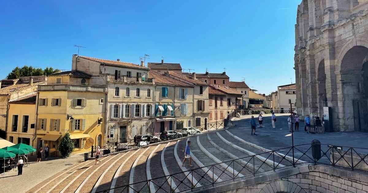 Elevated view of a historic old town with tiled roofs, towers, and winding streets under soft afternoon light