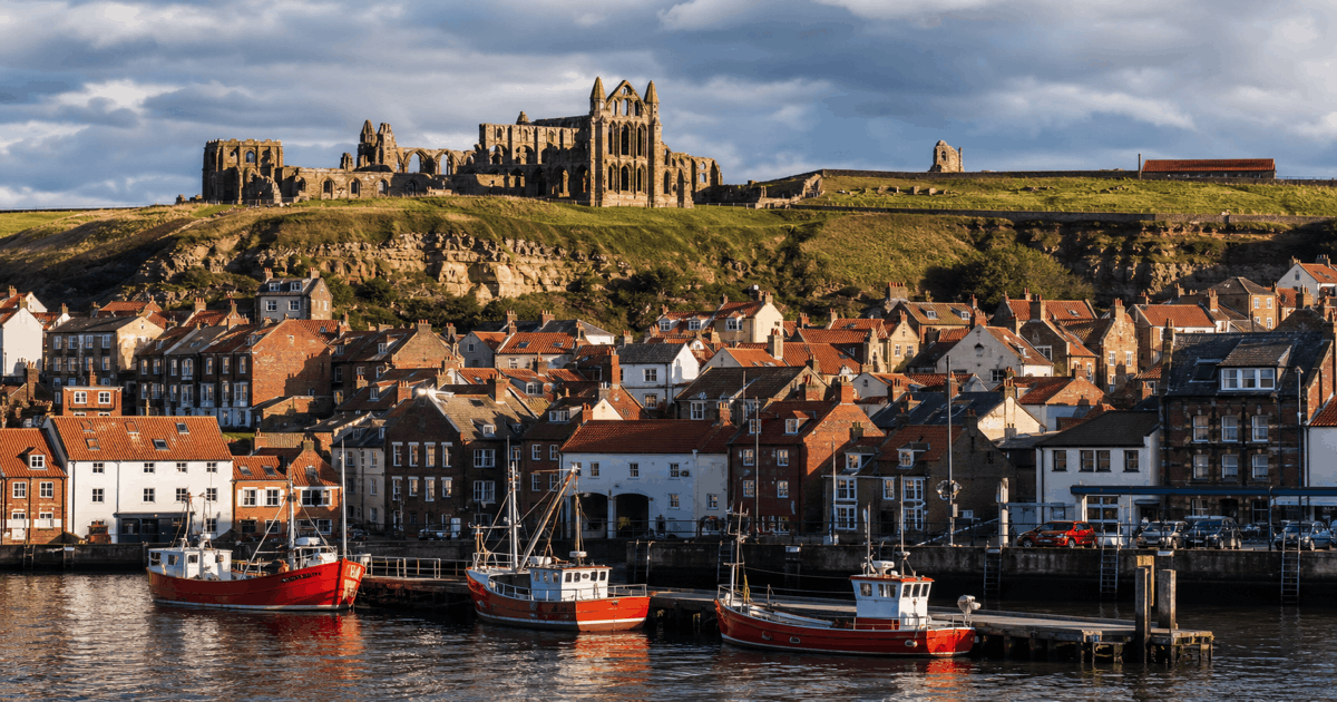 Whitby Abbey ruins on the cliff above the harbour and old town rooftops